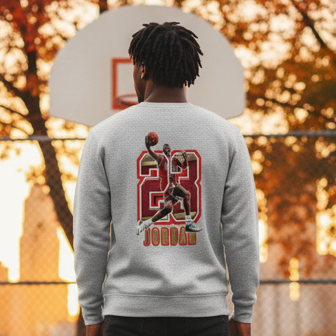Person wearing a sweatshirt with a basketball player design on a basketball court at sunset.